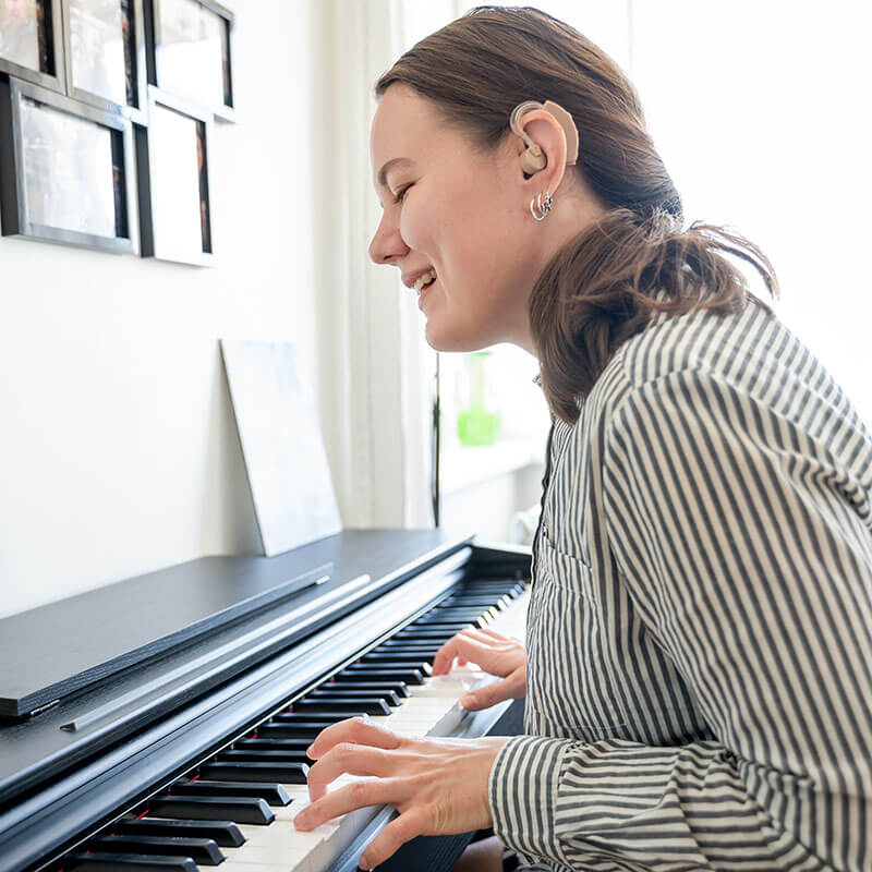 woman wearing a hearing aid playing the piano